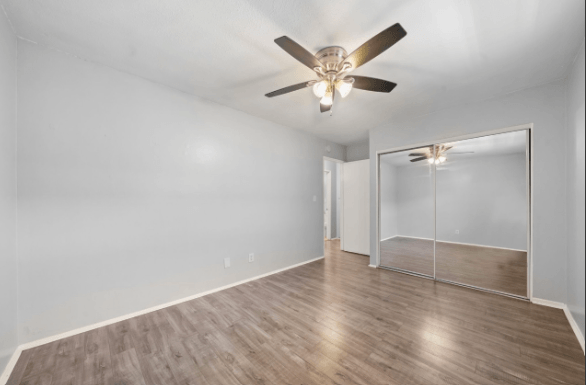 A room with a ceiling fan and a mirror on the wall.